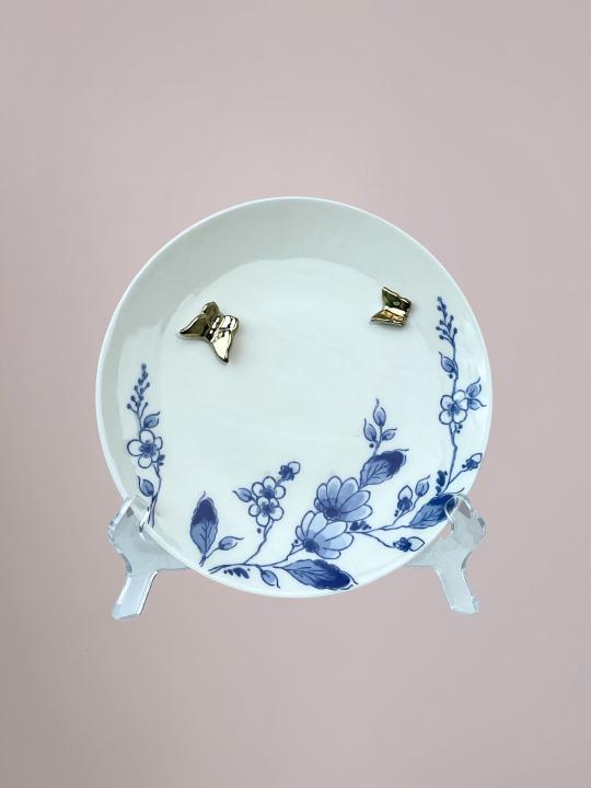 Delfts blauw wandbord van Heinen met blauwe bloemen langs de rand en 3D gouden vlinders op wit keramiek