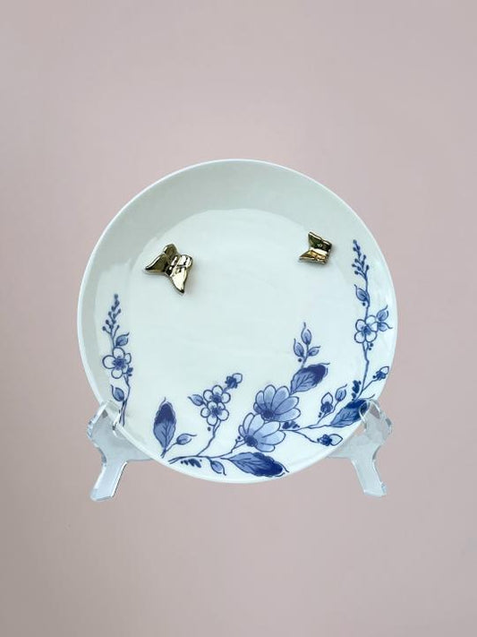 Delfts blauw wandbord van Heinen met blauwe bloemen langs de rand en 3D gouden vlinders op wit keramiek