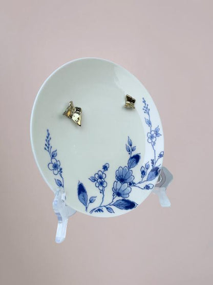 Delfts blauw wandbord van Heinen met blauwe bloemen langs de rand en 3D gouden vlinders op wit keramiek