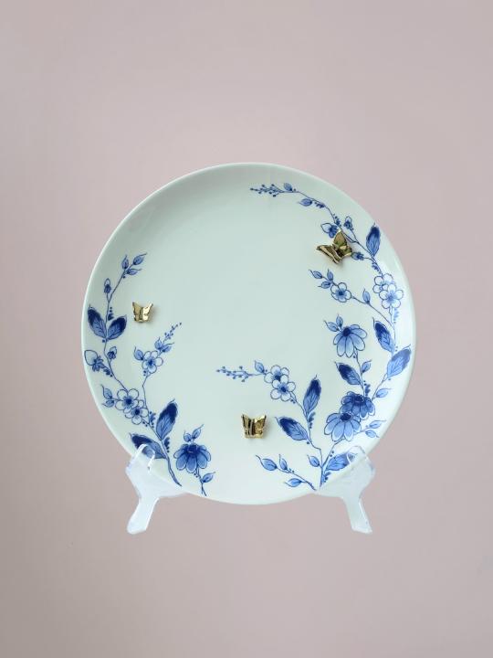 Delfts blauw wandbord van Heinen met blauwe bloemen langs de rand en 3D gouden vlinders op wit keramiek