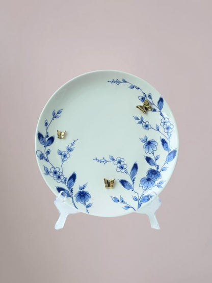 Delfts blauw wandbord van Heinen met blauwe bloemen langs de rand en 3D gouden vlinders op wit keramiek