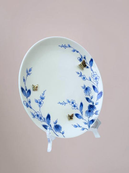 Delfts blauw wandbord van Heinen met blauwe bloemen langs de rand en 3D gouden vlinders op wit keramiek