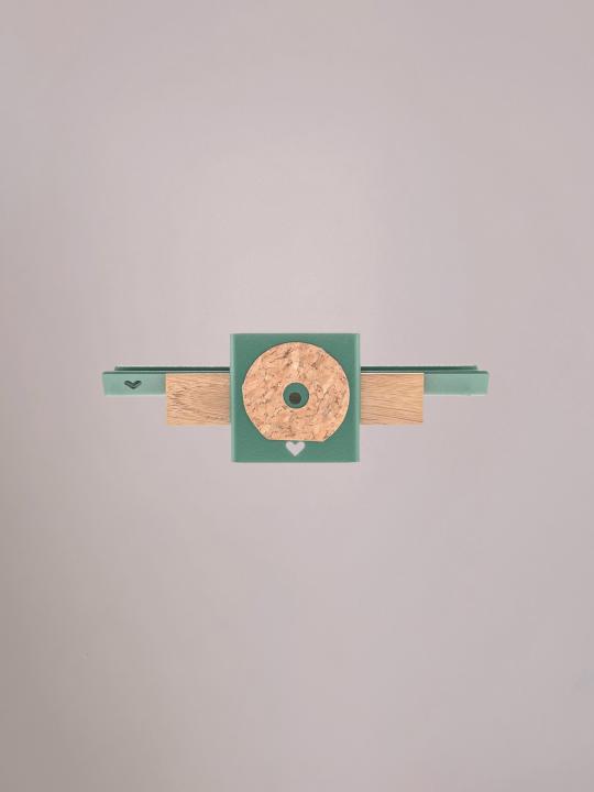 Achterzijde van het groene wandplankje met ophangpunten.