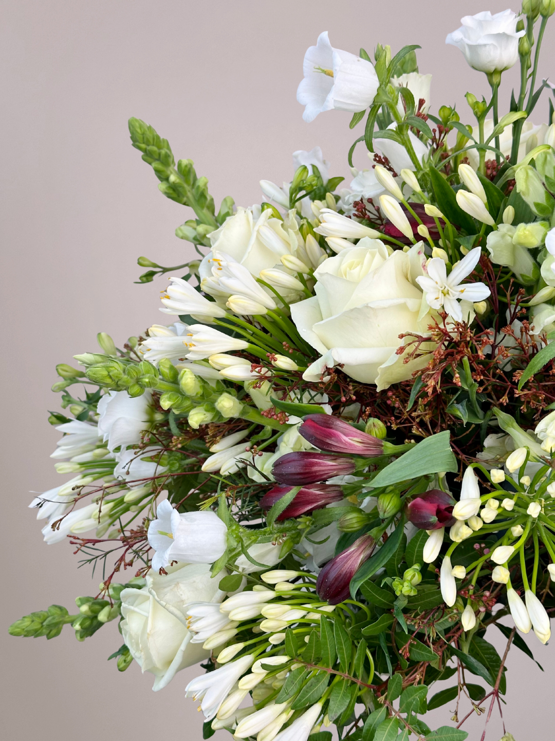 Wit rouwboeket met rozen en witte bloemen en subtiel donkerrode takken in het bloemstuk uit Zwolle.
